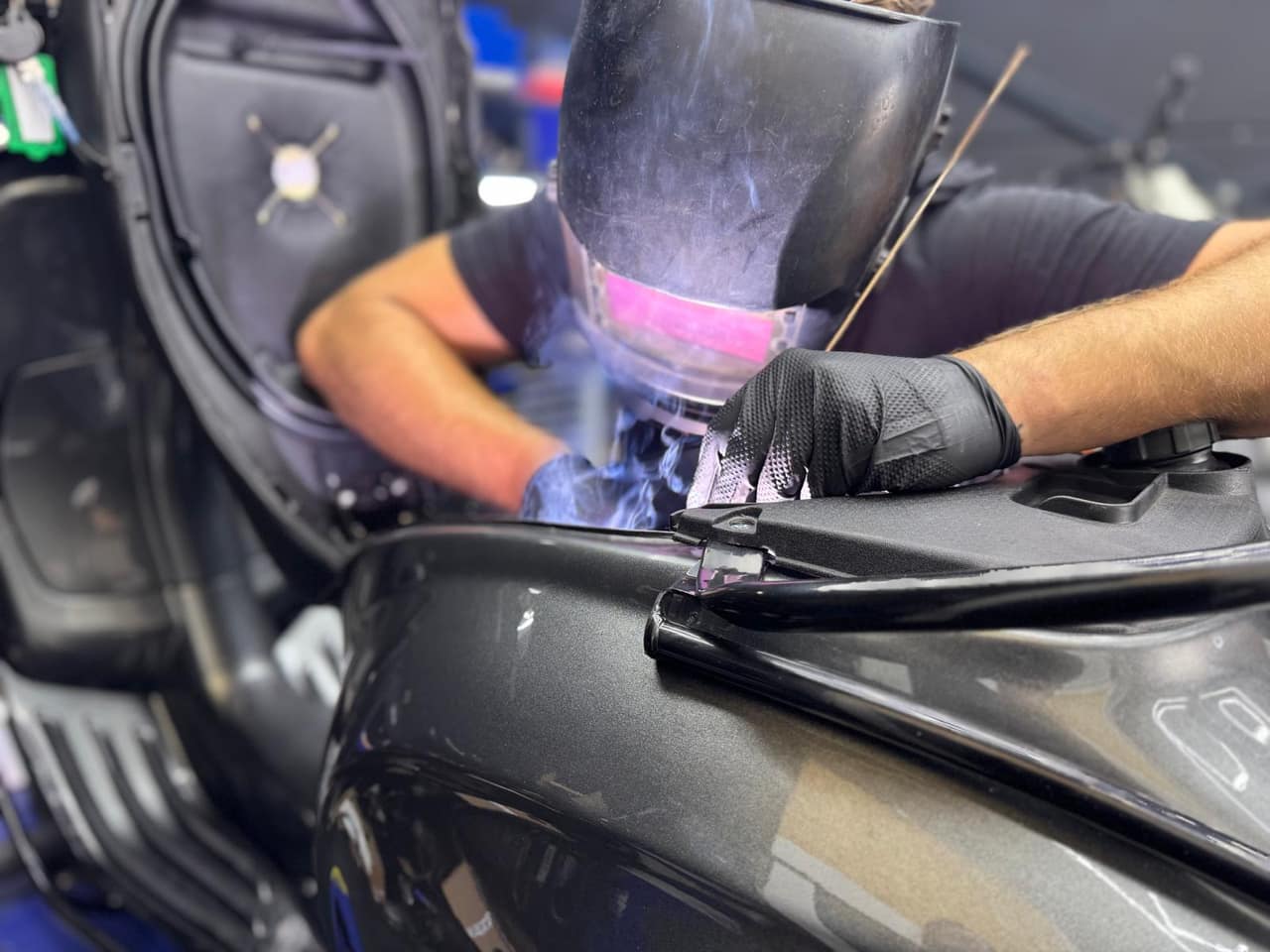Monteur met lasmasker aan het lassen aan een scooterframe